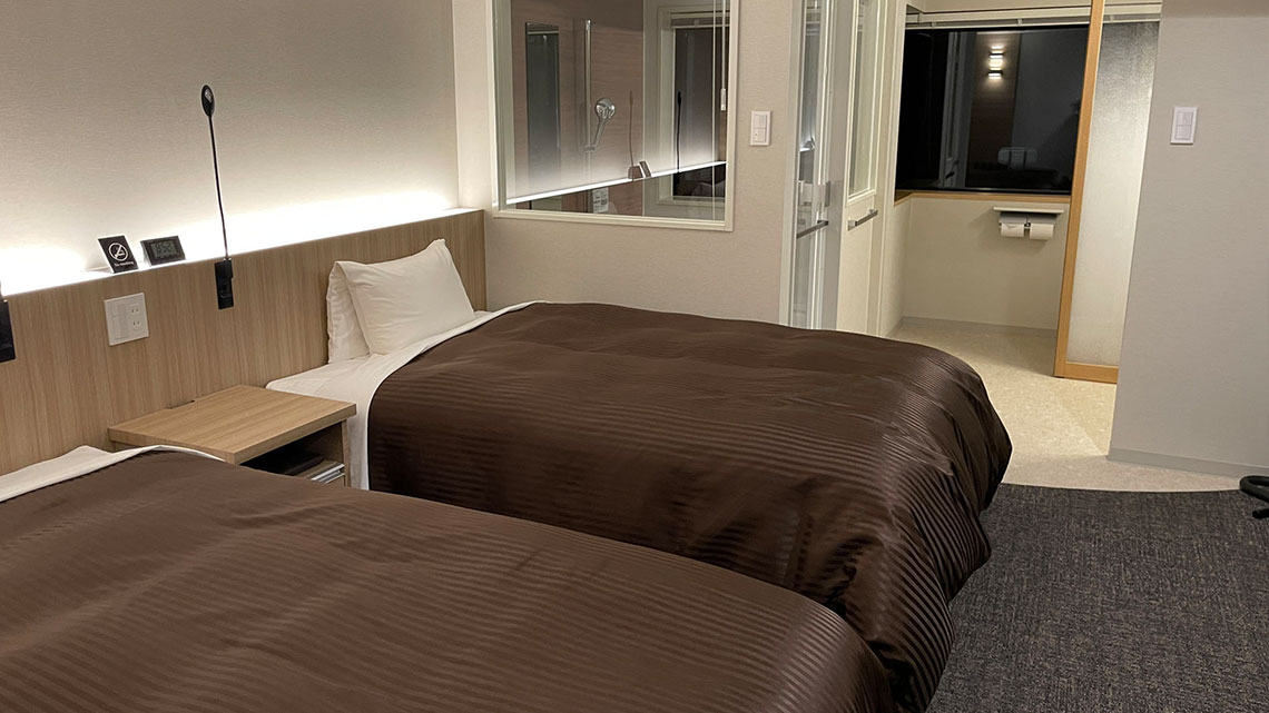 Twin beds in a hotel room with a shower in the back