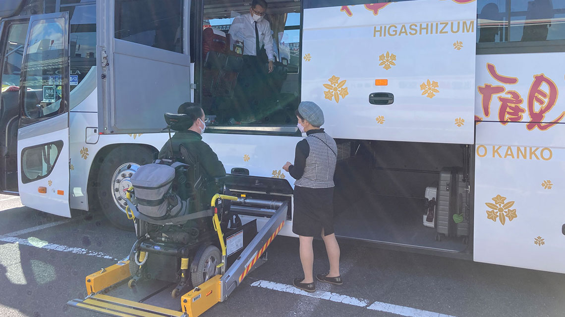 Wheelchair lift on the side of a coach bus with bus staff