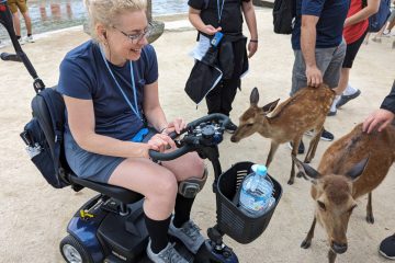 Anne de Ridder in her mobility scooter with deer from Miyajima in Hiroshima