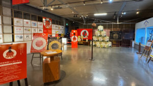 Display room featuring sake barrels, modern advertising panels, and informational exhibits about sake production