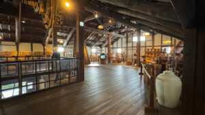 Wooden second floor with displays of brewing tools, mannequins, and rope equipment under a rustic roof