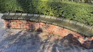 Curved brick bench, set beside trimmed hedges, offering a resting spot.