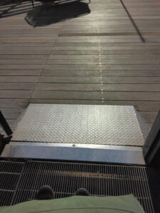 Gentle metal slope leading from the Glasshouse to the wooden deck outside.