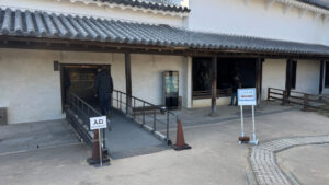 An entrance to the exhibition area with a ramp for accessibility, bordered by railings.