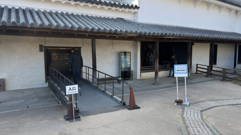 An entrance to the exhibition area with a ramp for accessibility, bordered by railings.