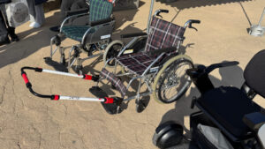 Closer view of the wheelchairs, with the middle one featuring front handles for pulling assistance on slopes.